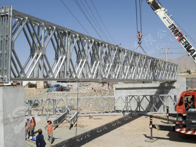 Crane lifting modular steel bridge span for rapid mission bridge assembly
