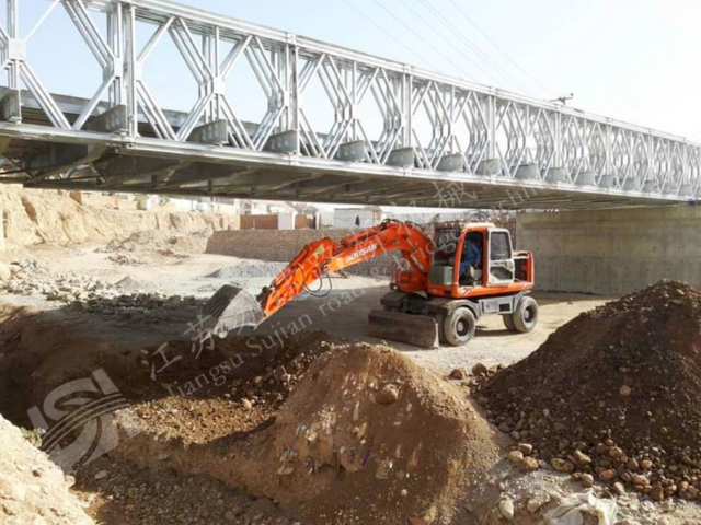 Heavy duty steel truss bridge over dry riverbed for construction and rescue access