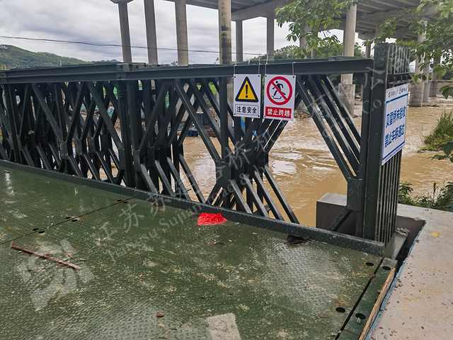 Temporary steel rescue bridge with warning signs for flood control projects