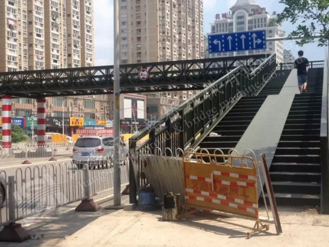 Urban Bailey footbridge with stair access beside a municipal roadway