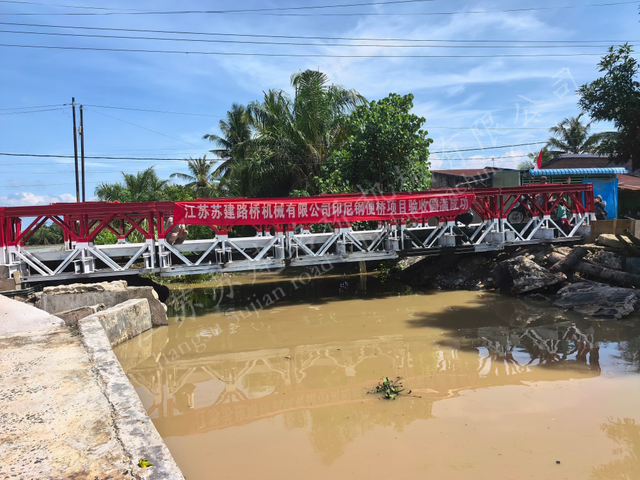 Red modular Bailey bridge in Indonesia restoring flood damaged rural traffic